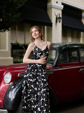 a lady wears a maxi strap dress with black and white floral print design